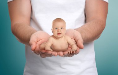 Surrogacy concept. Man holding cute little baby on color background, closeup clipart