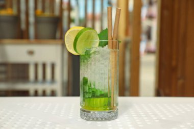 Glass of refreshing citrus drink on white table indoors