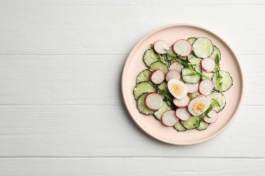 Tasty fresh salad with cucumber on white wooden table, top view. Space for text