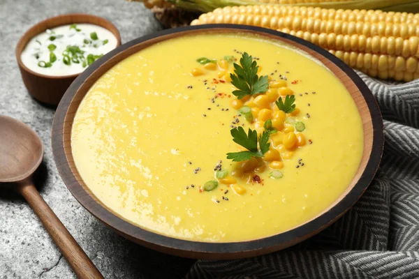 Delicious creamy corn soup served on grey table