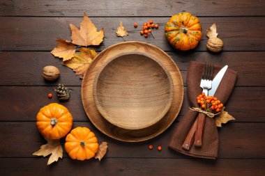 Seasonal table setting with pumpkins and autumn leaves on wooden background, flat lay. Thanksgiving Day