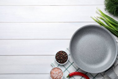 Flat lay composition with frying pan and fresh products on white wooden table, space for text