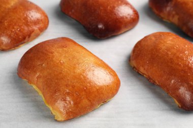 Delicious baked pirozhki on parchment paper, closeup