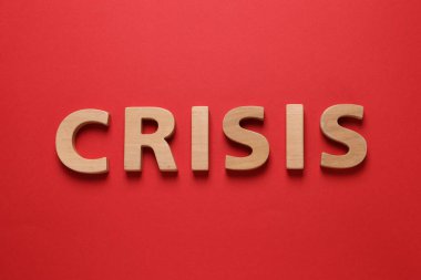 Word Crisis made of wooden letters on red background, flat lay