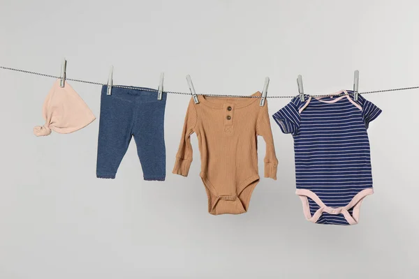 Different Baby Clothes Drying Laundry Line Light Background — Stok fotoğraf