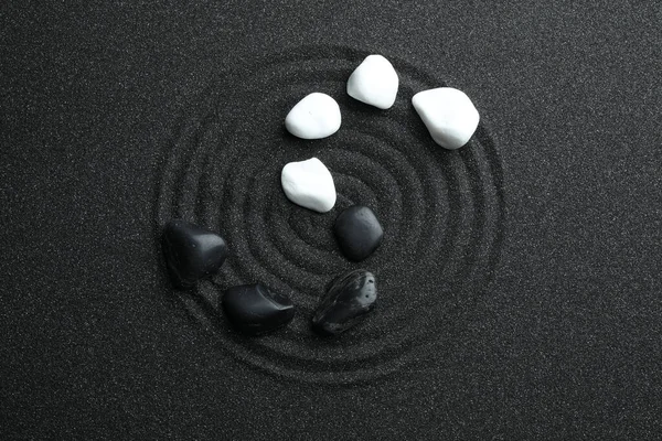 Stones on black sand with beautiful pattern, flat lay. Zen and harmony