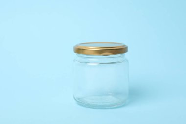 Closed empty glass jar on light blue background