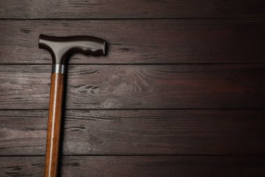Elegant walking cane on wooden table, top view. Space for text