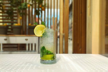 Glass of refreshing citrus drink on white table indoors