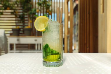 Glass of refreshing citrus drink on white table indoors