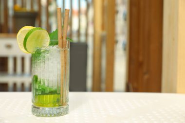 Bir bardak ferahlatıcı narenciye içeceği beyaz masa içinde, mesaj için yer var.