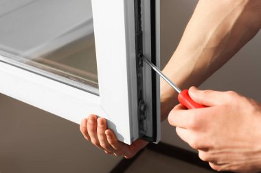 Worker adjusting installed window with screwdriver indoors, closeup