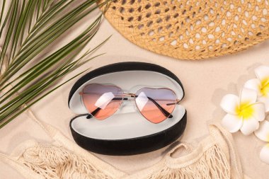 Flat lay composition with stylish sunglasses in black leather case on sand