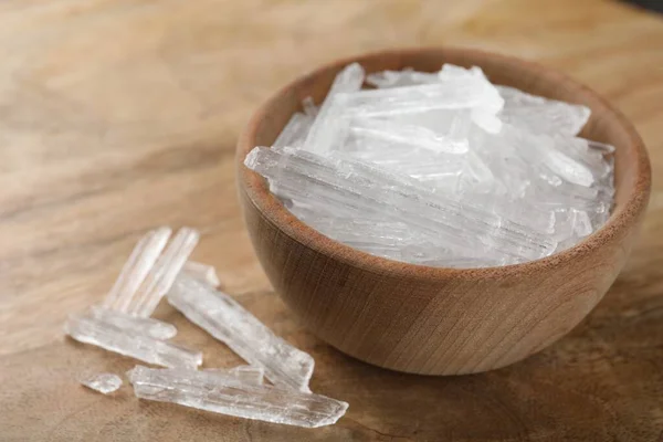 Menthol crystals in bowl on wooden background