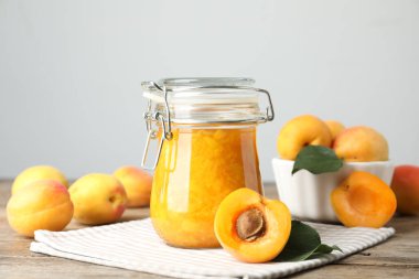 Kayısı reçeli kavanozu ve ahşap masada taze meyve.