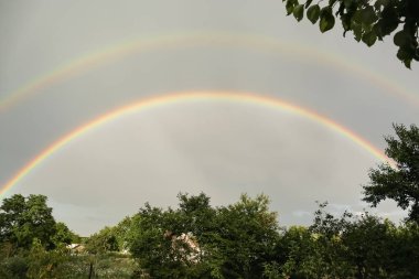 Beautiful view of countryside and double rainbow in cloudy sky