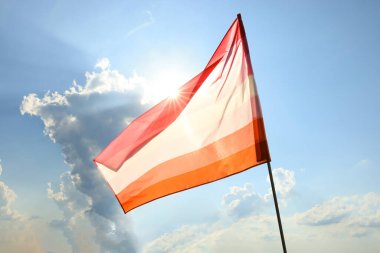 Bright lesbian flag fluttering against blue sky