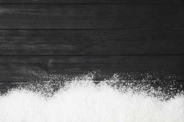 Artificial snow on black wooden background, top view with space for text. Christmas decor