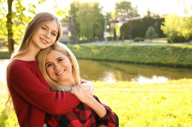 Mutlu anne kızıyla birlikte güneşli bir günde parkta vakit geçiriyor.