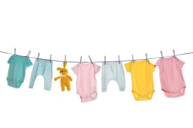 Colorful baby clothes and toy drying on laundry line against white background