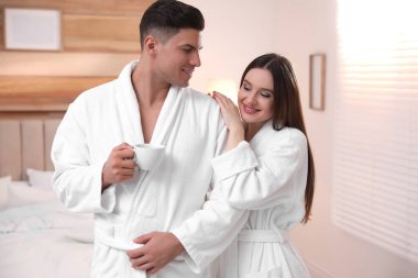 Yatak odasında kahveli bornozlu mutlu bir çift.