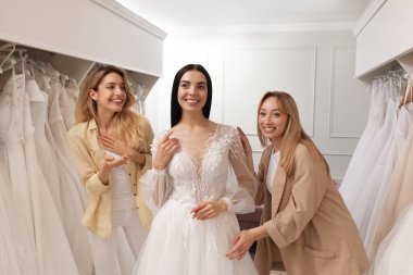 Gelin ve arkadaşları butikte gelinlik seçiyor.