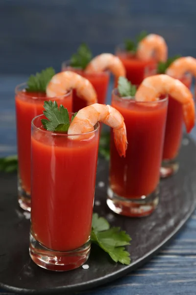 Glasses of shrimp cocktail with tomato sauce on slate board