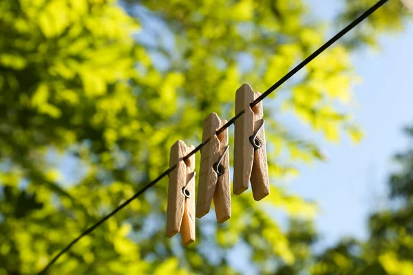 Wooden clothespins hanging on washing line outdoors
