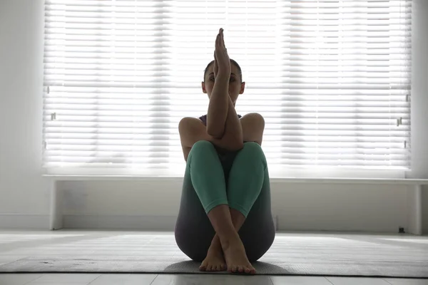 Woman practicing eagle asana in yoga studio. Garudasana pose