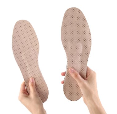 Woman holding pair of pink orthopedic insoles on white background, closeup