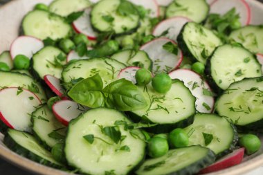Appetizing salad with cucumbers, radish and pea in bowl, closeup