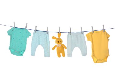 Colorful baby clothes and toy drying on laundry line against white background