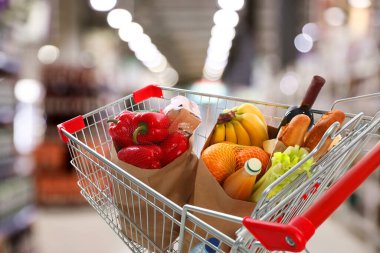 Shopping cart with different groceries in supermarket