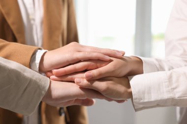 Group of people holding hands together indoors, closeup. Unity concept
