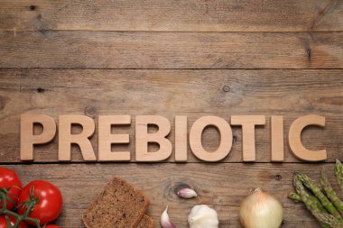 Word Prebiotic made of letters and foodstuff on wooden table, flat lay. Space for text