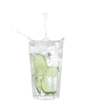 Water with sliced lime splashing out of glass on white background