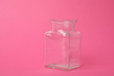 Open empty glass jar on pink background