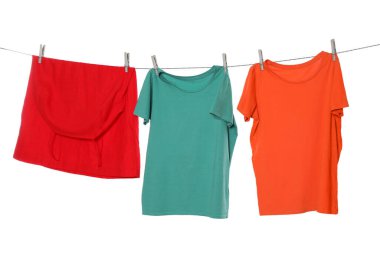 Different bright clothes drying on washing line against white background