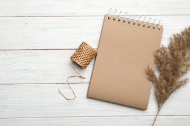 Beyaz ahşap masa üzerinde şık bir Kraft defter ve dekor elementleri var. Metin için boşluk