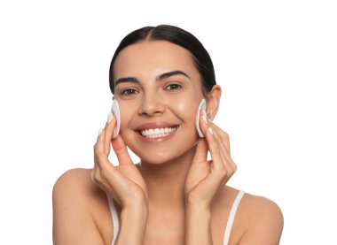 Young woman using cotton pads with micellar water on white background
