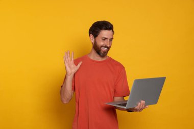 Handsome man with laptop on orange background