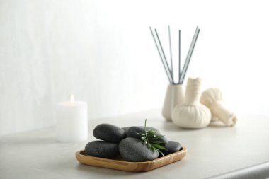 Spa stones and green leaf on light grey table