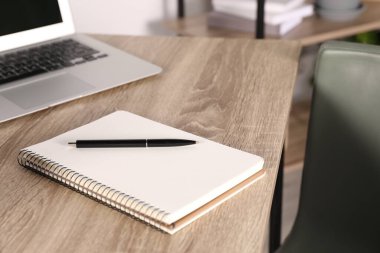 Notebook, pen and laptop on wooden table indoors
