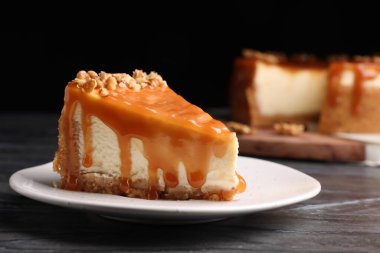 Piece of delicious cake with caramel and walnuts on black marble table, closeup