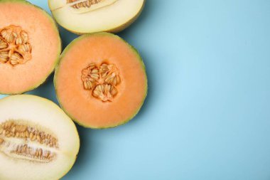 Tasty colorful ripe melons on light blue background, flat lay. Space for text