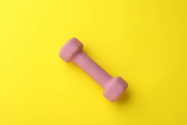 Stylish dumbbell on yellow background, top view