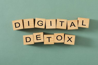 Wooden cubes with words DIGITAL DETOX on green background, flat lay