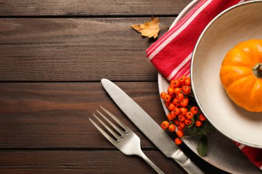 Top view of seasonal table setting with pumpkin and ashberries on wooden background, space for text. Thanksgiving Day