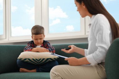 Psychologist working with unhappy little boy in office. Mental health problems