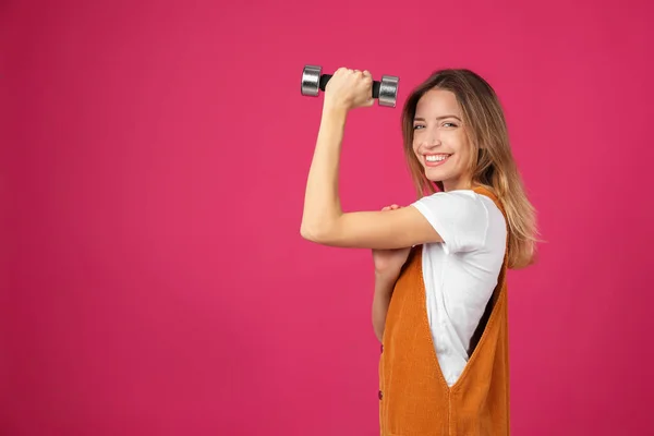 Woman with dumbbell as symbol of girl power on pink background, space for text. 8 March concept